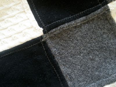 two pieces of black and grey wool sitting on top of a white bed coverlet