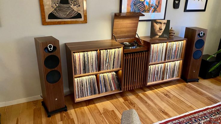 an entertainment center with record players, speakers and pictures on the wall