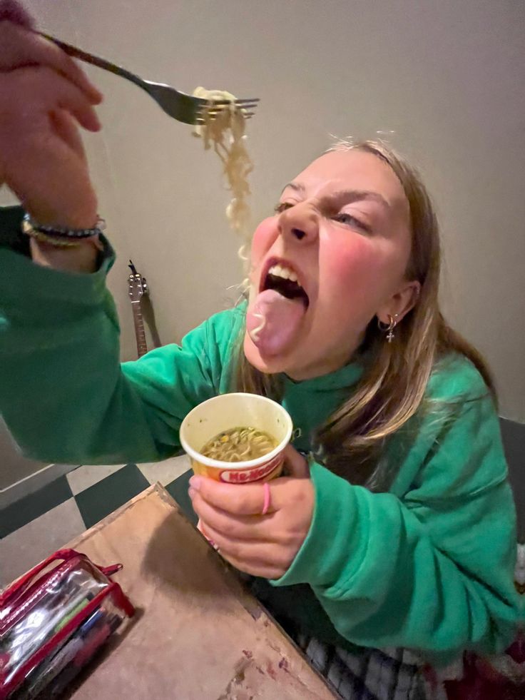 a woman is eating noodles from a bowl