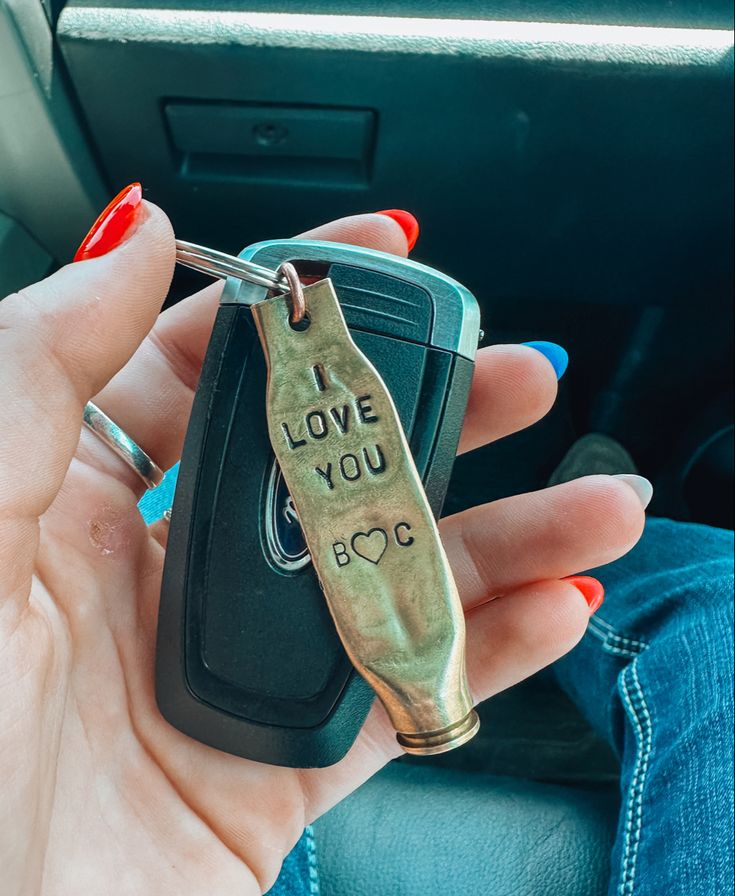 a woman holding a car key with the word love you to go written on it