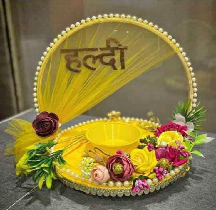 a yellow hat with flowers on it sitting on top of a table next to a mirror