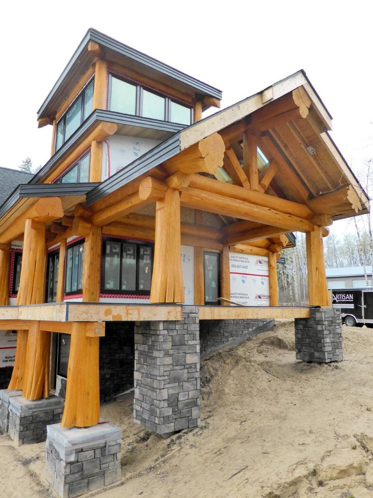 a large wooden structure sitting on top of a pile of dirt next to a building