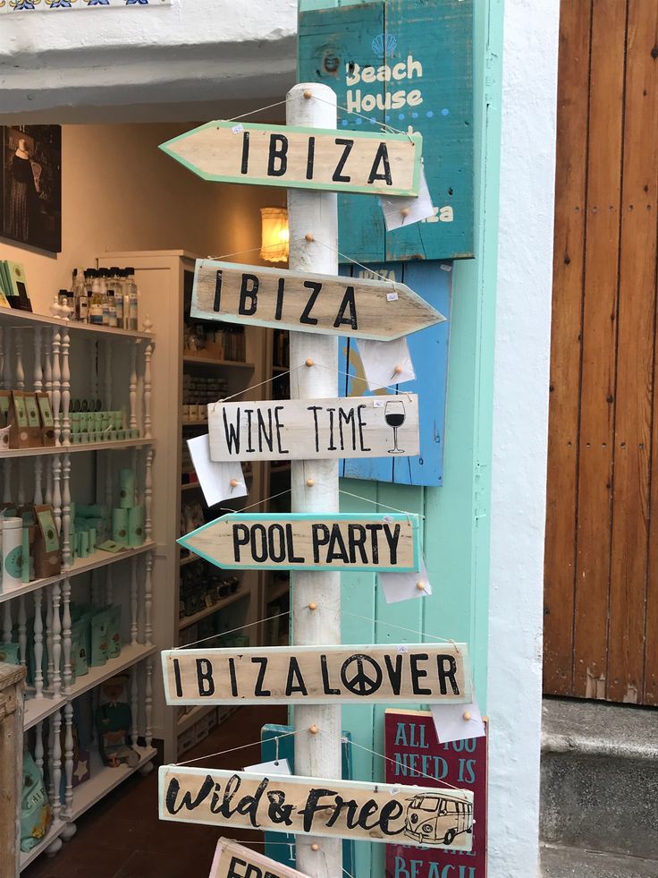 there are many signs on the pole in front of this store that say wine time, pool party, and pizza lover