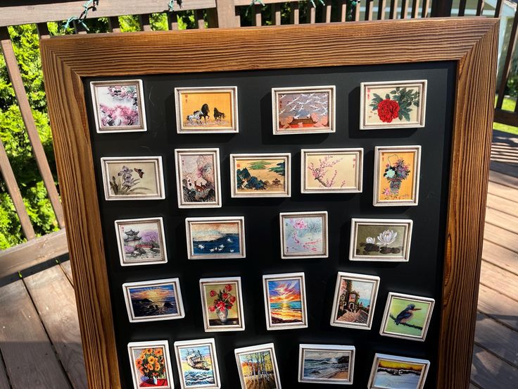 a wooden frame filled with pictures on top of a wooden floor next to a fence