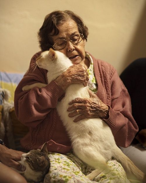 an older woman holding a cat in her arms