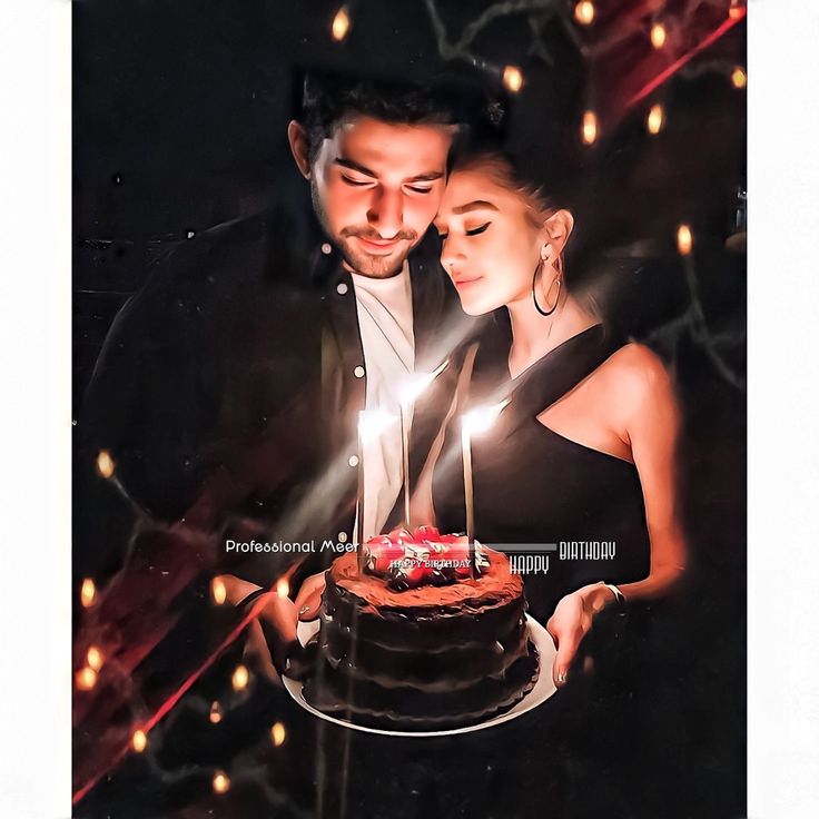 a man and woman standing next to each other in front of a cake with lit candles