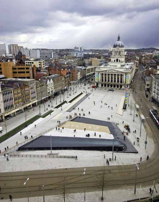 an aerial view of a city square with people walking around and buildings in the background