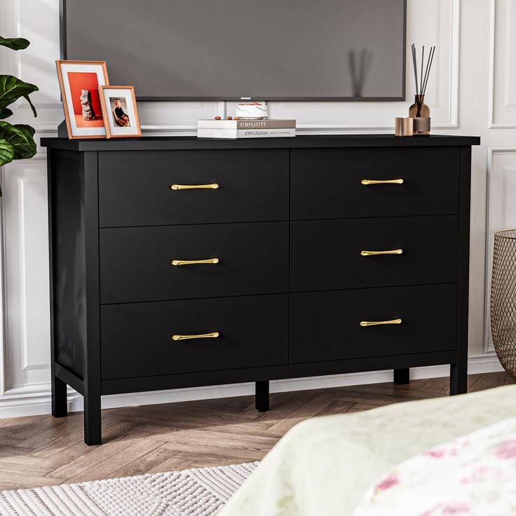 a black dresser with gold handles in front of a flat screen tv