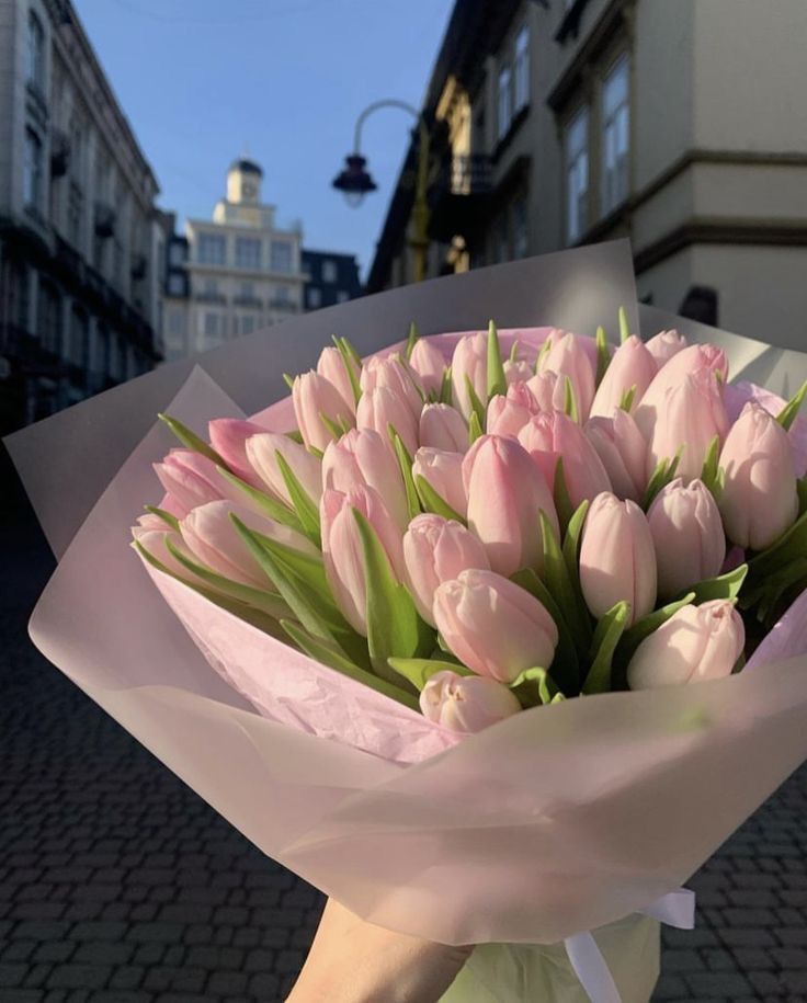 a bouquet of pink tulips is wrapped in white paper