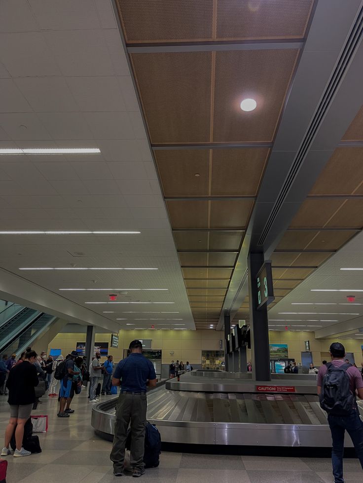 people waiting in line for their luggage at the baggage claim area on an empty airport