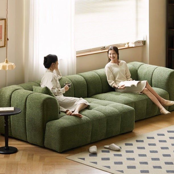 two women sitting on green couches in a living room