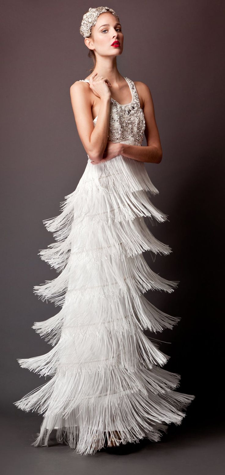 a woman in a white dress with feathers on her head and hands behind her back