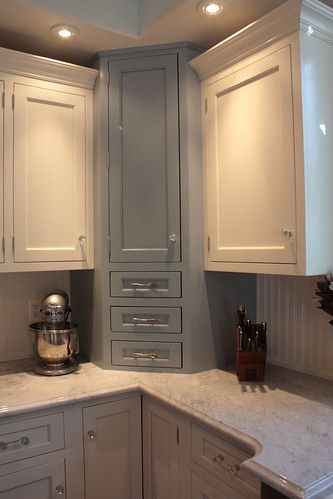 a kitchen with white cabinets and marble counter tops