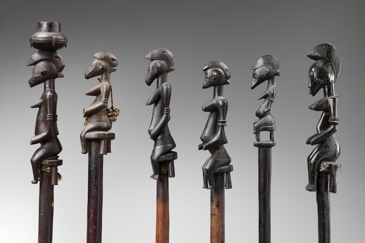 an assortment of african carved wooden figures in various styles and sizes, all standing side by side