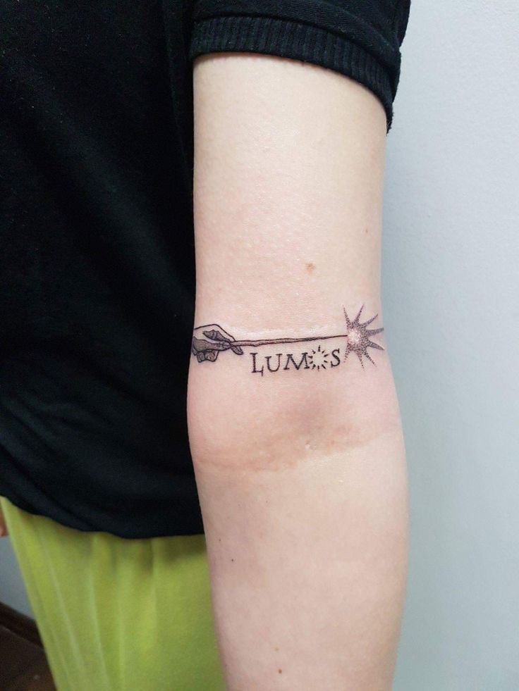 a person with a tattoo on their arm that says lumoss and an arrow