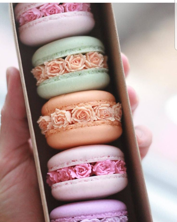 a box filled with macaroons covered in pink and green frosting