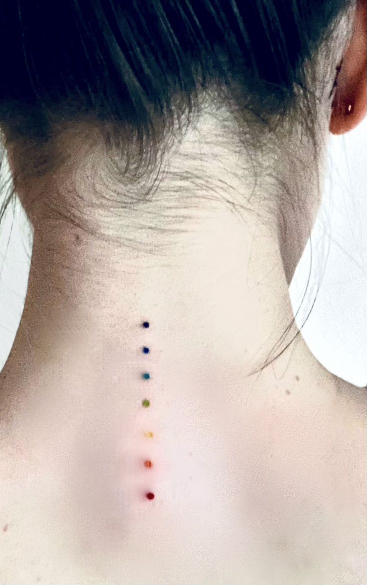 the back of a woman's neck with colorful dots on her left and right side