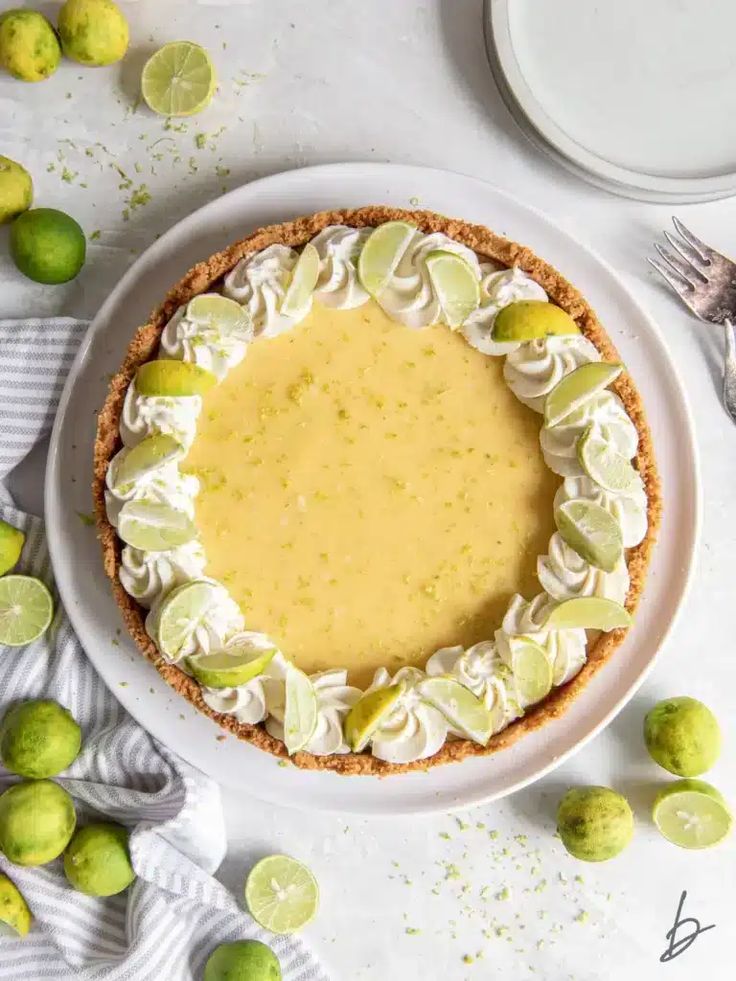 a lemon pie on a white plate with limes around it