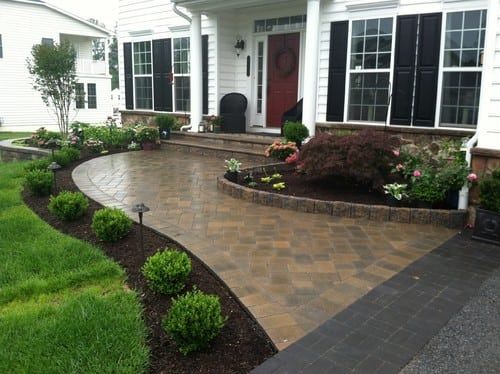 a brick walkway leading to a white house