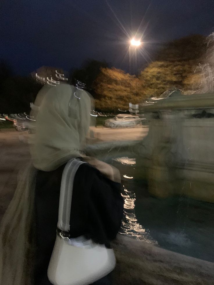 a woman walking down the street carrying a white purse