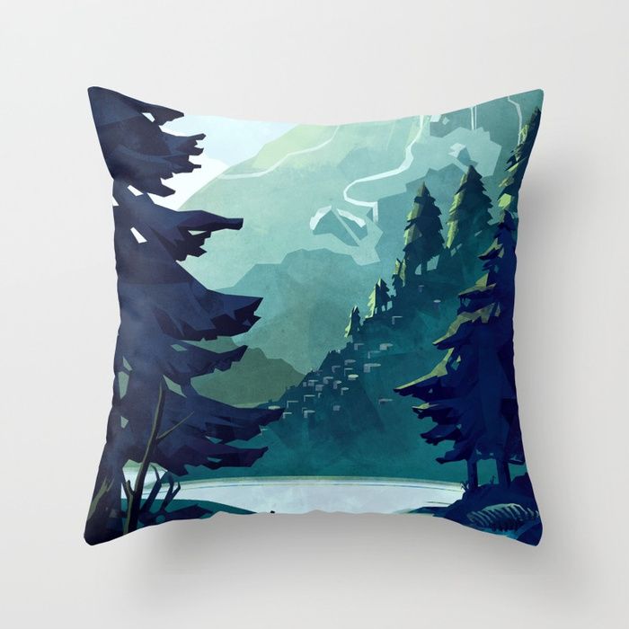 a blue pillow with trees and mountains in the background