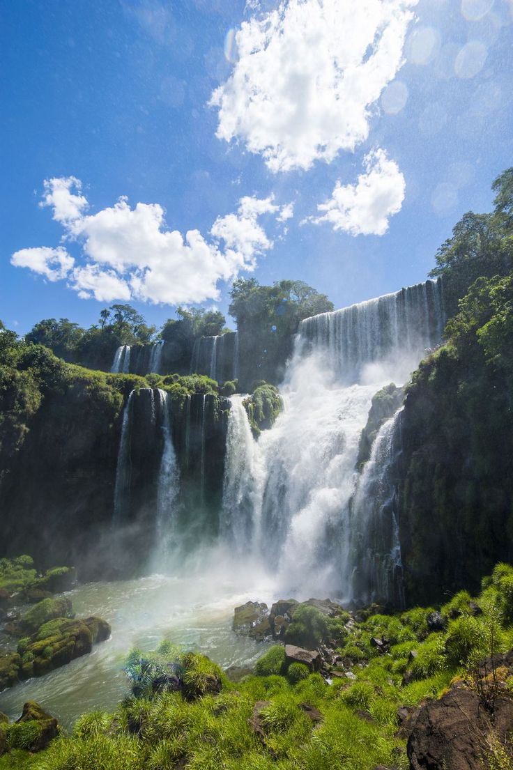 a large waterfall in the middle of a lush green forest