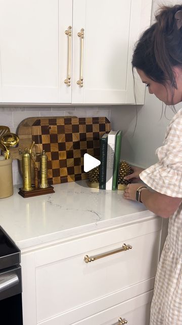 a woman standing in front of a kitchen counter with a book on top of it