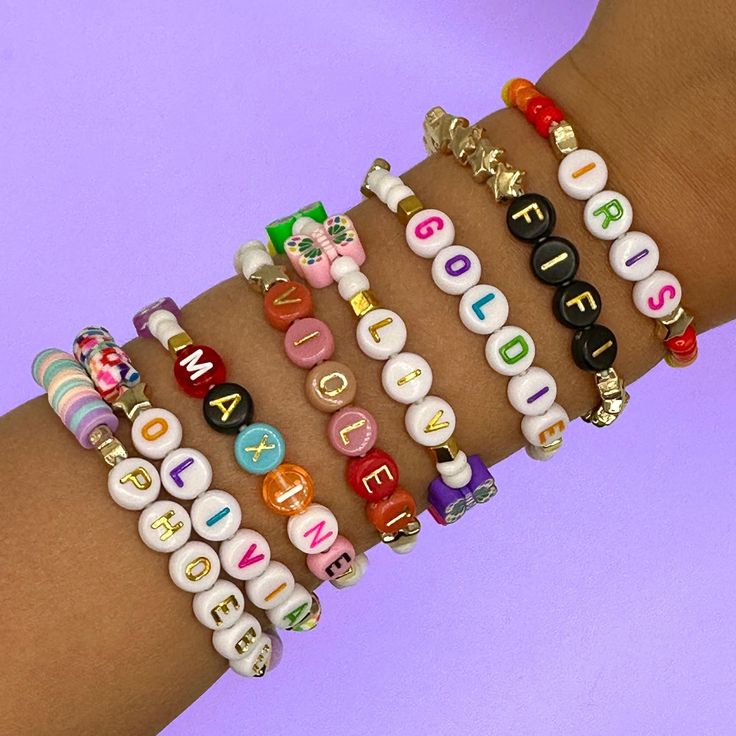 a woman's arm with several bracelets that have letters and numbers on them