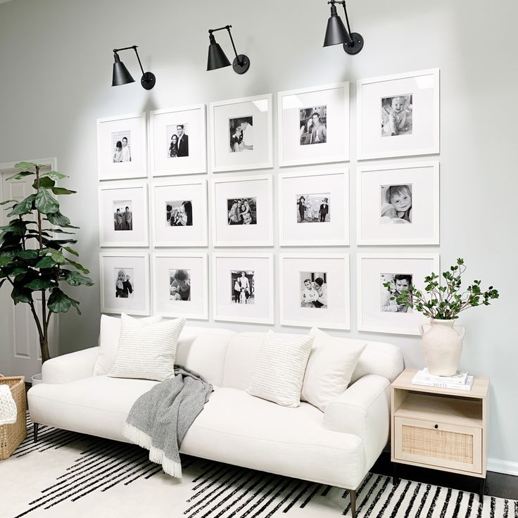 a living room with white furniture and pictures on the wall above it's couch