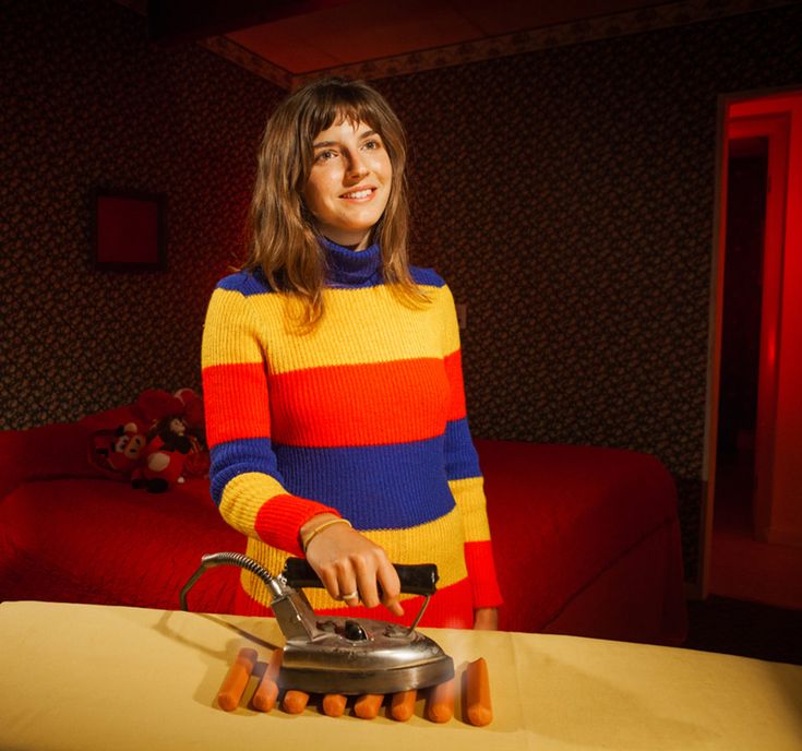 a woman standing next to a table holding a tea kettle