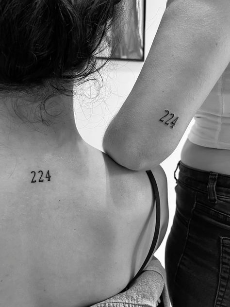 two women with tattoos on their backs, one is holding the other's hand