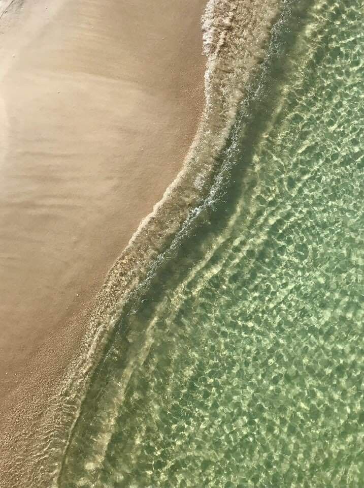 an aerial view of the ocean and beach with waves coming in from the water,