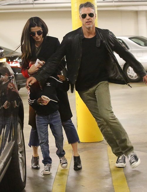 the man and woman are walking through an airport parking lot with their child in tow