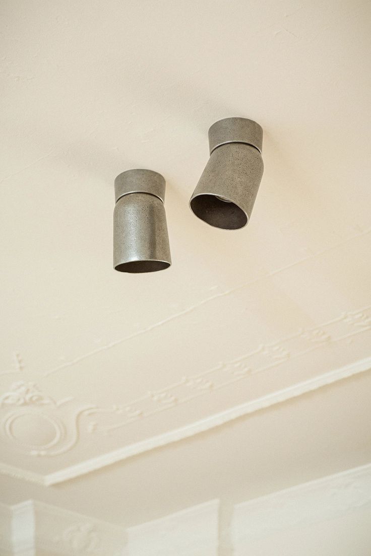 two metal cups hanging from the ceiling in a room with white painted walls and ceilings