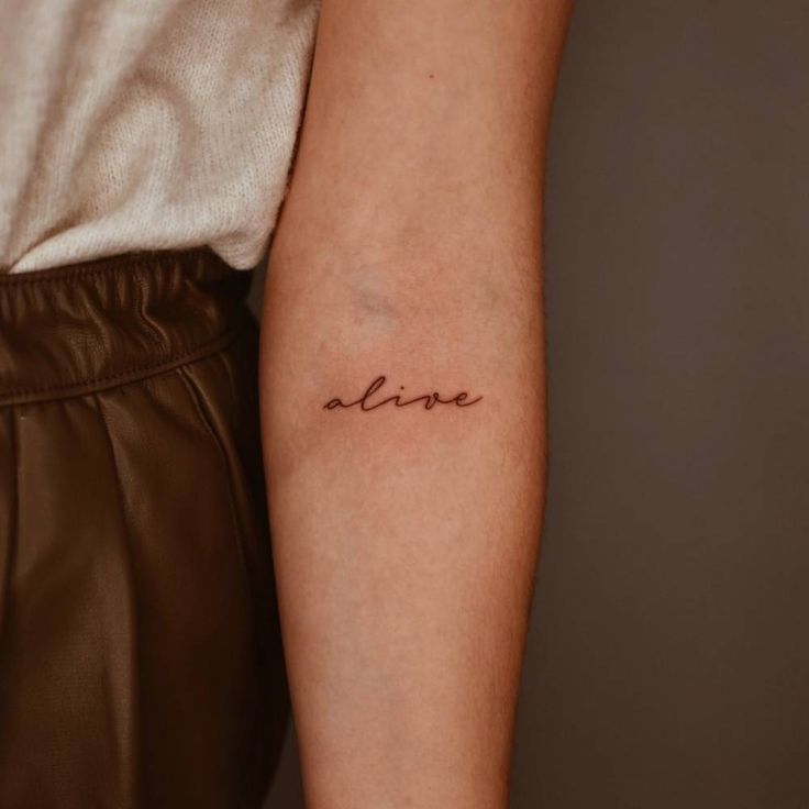 a woman's arm with the word love tattooed on her left arm, in cursive font