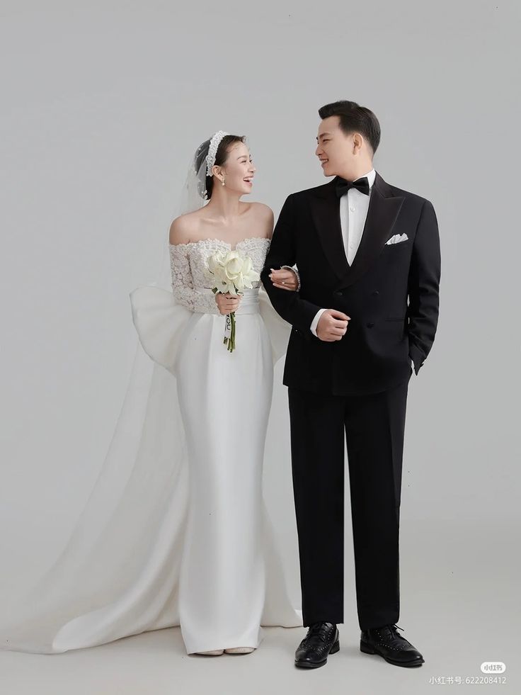 a bride and groom standing next to each other in front of a white backdrop with the words, happy new year written on it