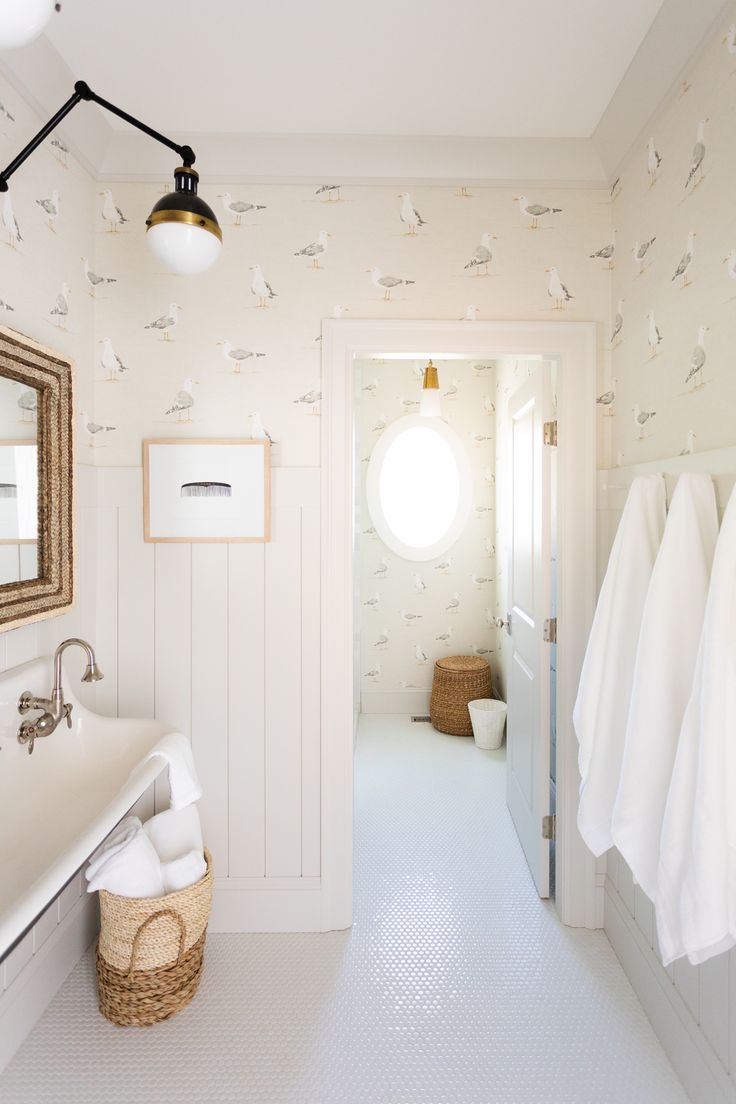 a bathroom with white walls and flooring next to a sink, mirror and towel rack