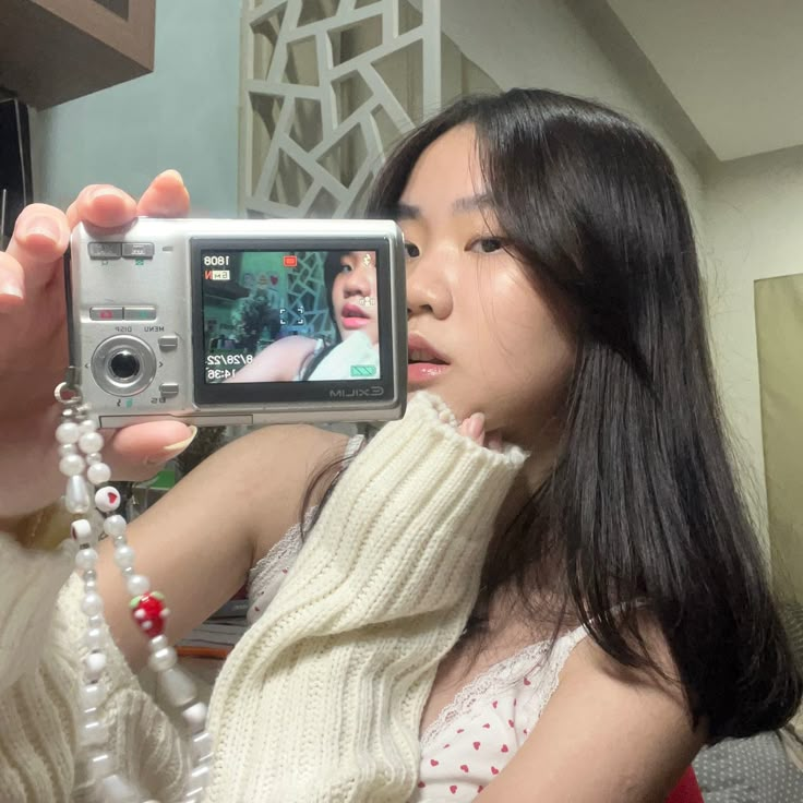 a woman holding up a camera to take a selfie in front of her mirror