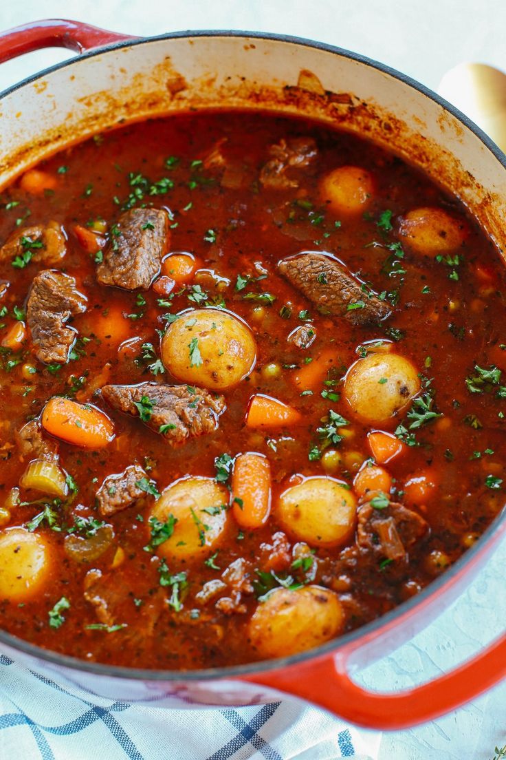 a red pot filled with stew on top of a table