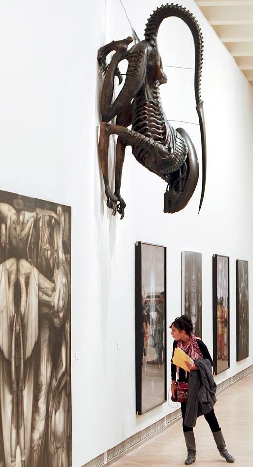 a woman is looking at art on display in a museum with sculptures hanging from the walls