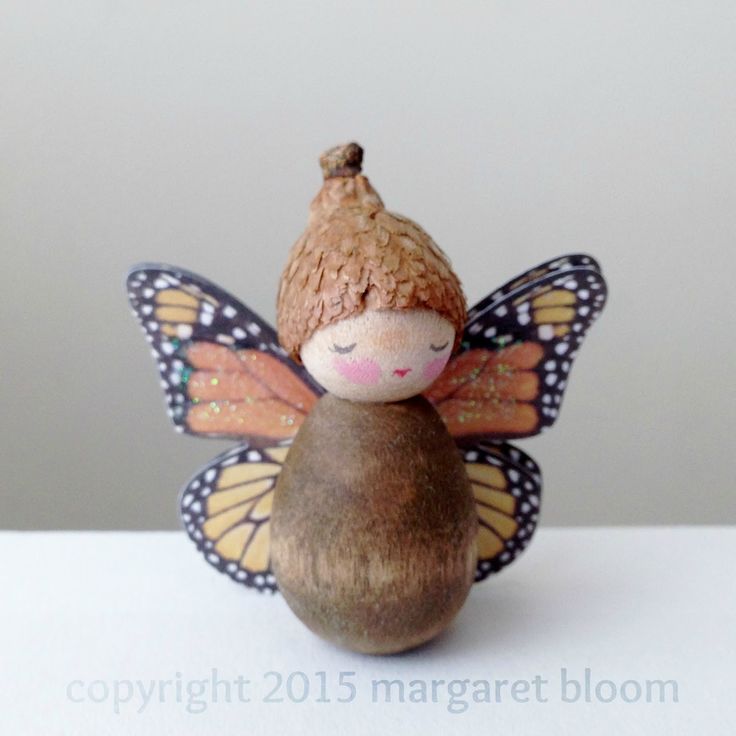 a small doll sitting on top of a wooden ball next to a butterfly figurine