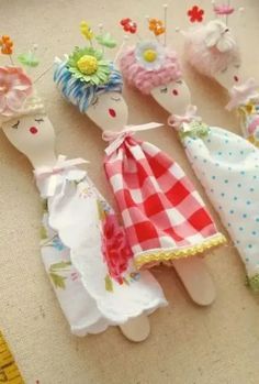 four little dolls are sitting next to each other on a piece of cloth with pins