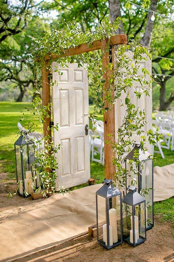 an outdoor ceremony set up with white chairs and greenery