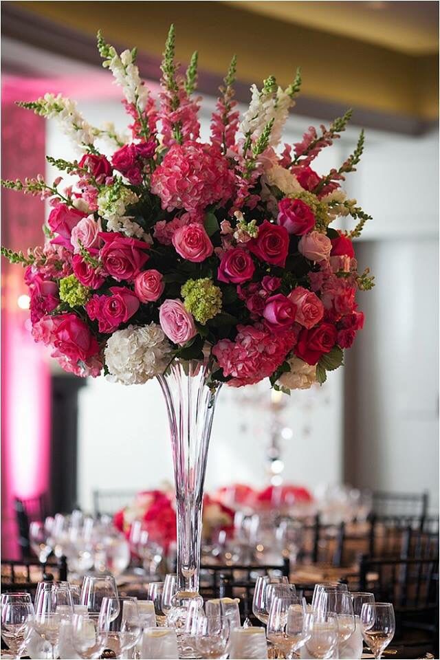 a tall vase filled with lots of pink and white flowers on top of a table