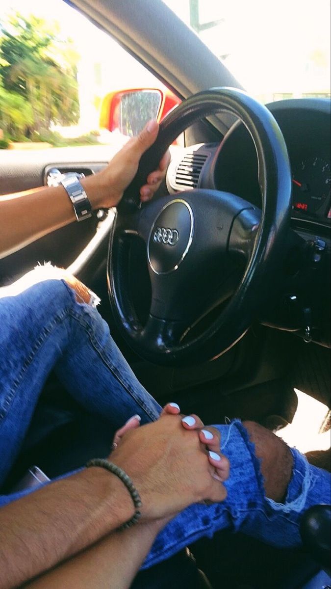 two people sitting in the driver's seat of a car with their hands on the steering wheel