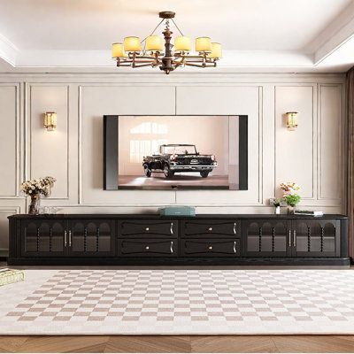 a living room with a large tv on the wall and a checkered rug in front of it