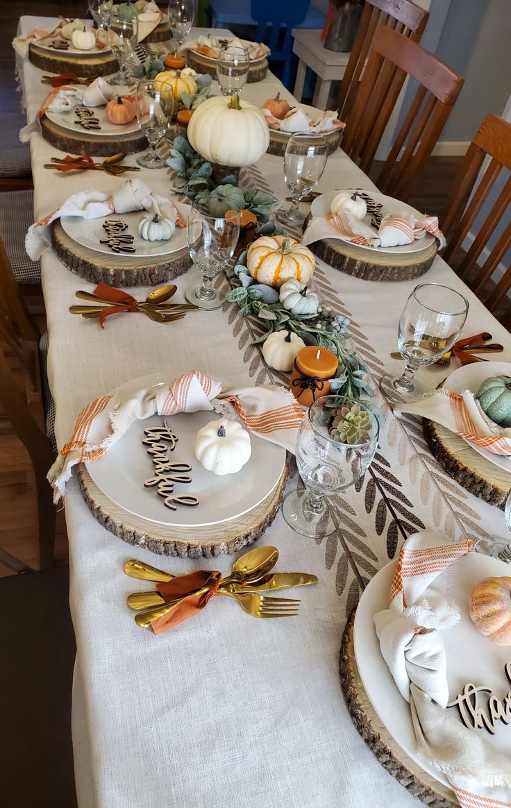 a table set for thanksgiving dinner with pumpkins and gourds