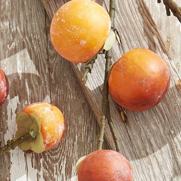 four oranges on a wooden surface with leaves