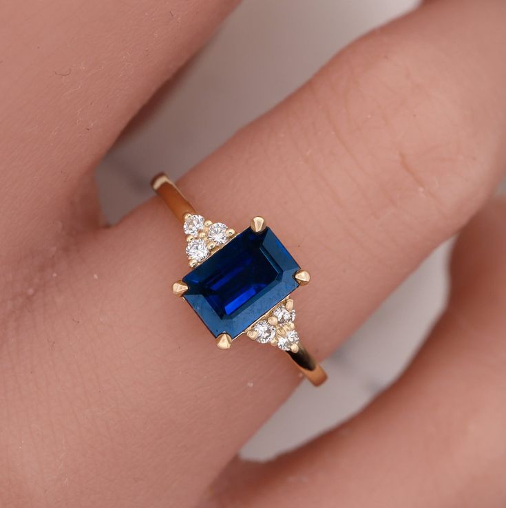 "Our new stunning design features an art deco ring set with natural delicate blue sapphire & natural diamonds, perfect ring for a daily wear and also great for engagement for sapphire lovers or people that were born in September 💛 Measurements: * Gem Stones: 100% Natural Sapphire * Center Stone Measurements: 7.00X5.00 m\"m * Color and Clarity: Clear Blue * Side Stones: 100% Natural Diamonds * Side Stones Measurements: 0.09ct D-F VS1-VS2 * Material: High-Quality Solid Gold 14/18k ------CUSTOMIZA Gold Sapphire Ring Engagement, Saphire Engament Ring Rectangle, Emerald Cut Sapphire Engagement Ring, Art Deco Sapphire Ring, Wedding Color Pallet, Dream Rings, Future Engagement Rings, Blue Sapphire Ring, Emerald Engagement Ring Cut