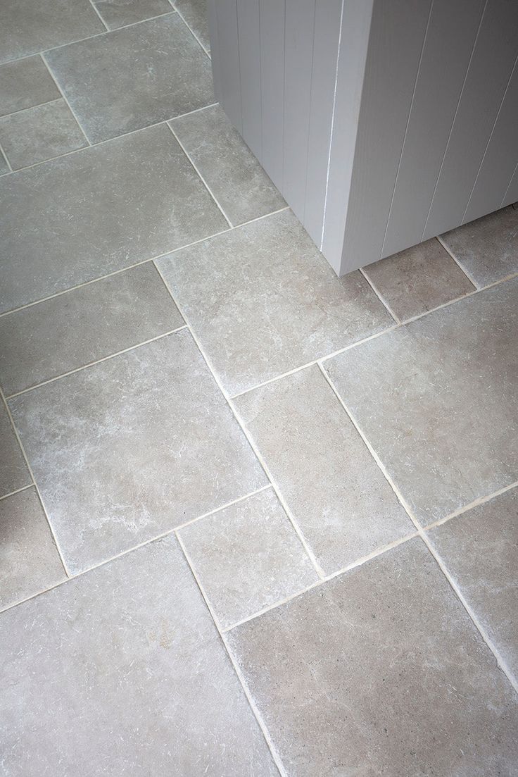 a tile floor in a bathroom next to a sink and toilet paper dispenser